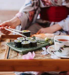 young-woman-in-japanese-kimono-holds-rolls-and-sus-L8YHSAK